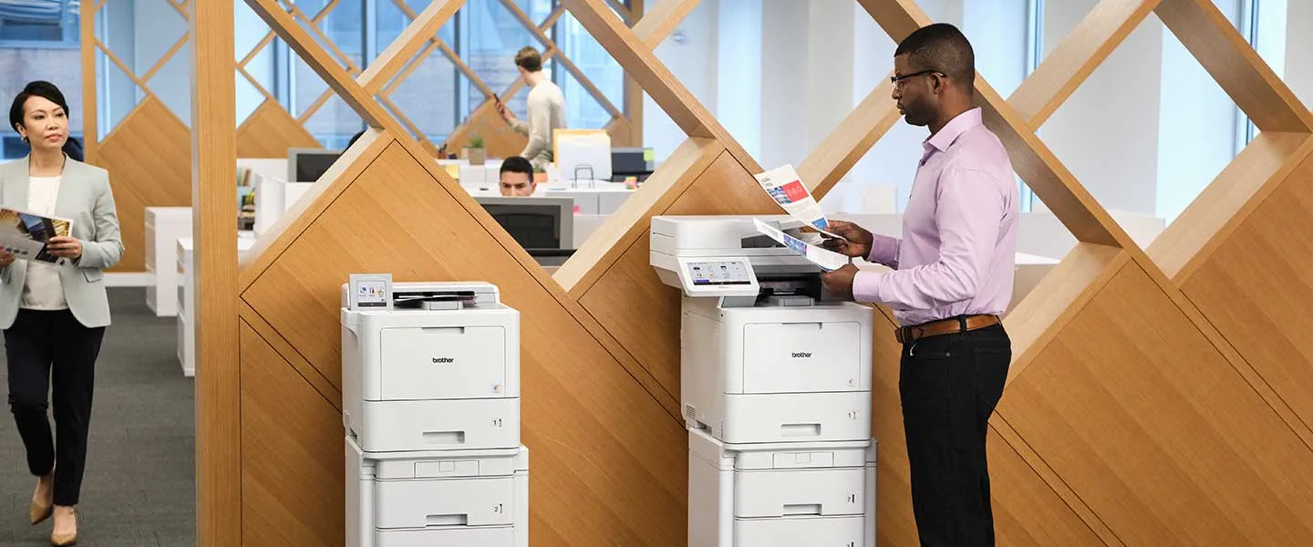 Man using Brother Workhorse series enterprise printer. Models shown HL-L9470 and MFC-L9670.